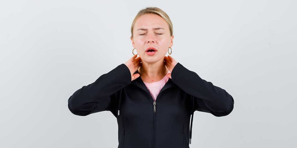 A woman winces in pain while clutching her neck, demonstrating the chronic physical discomfort risks of leaving whiplash injuries untreated.